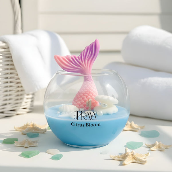 Round glass jar candle with blue wax, pink fish tail wick, and citrus bloom scent label.