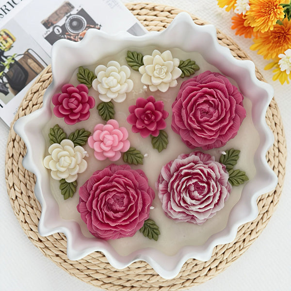 White scalloped bowl candle with pink and white 3D floral decorations and green leaves on a woven placemat.