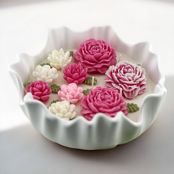 White ceramic candle bowl with scalloped edges holding pink and white floral wax candles.