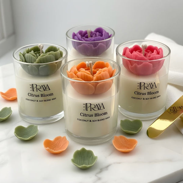 Set of three glass jars with orange, pink, and purple 3D heart-shaped flower candles on white marble surface.