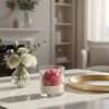 Glass jar candle with pink lotus flower-shaped wax in modern living room setting.