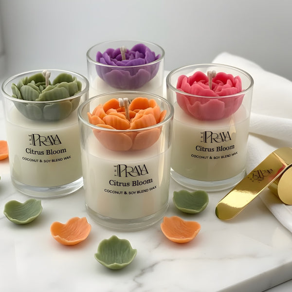 Three 3D heart flower jar candles in purple, orange, and pink with green and orange ceramic heart dishes on marble surface.
