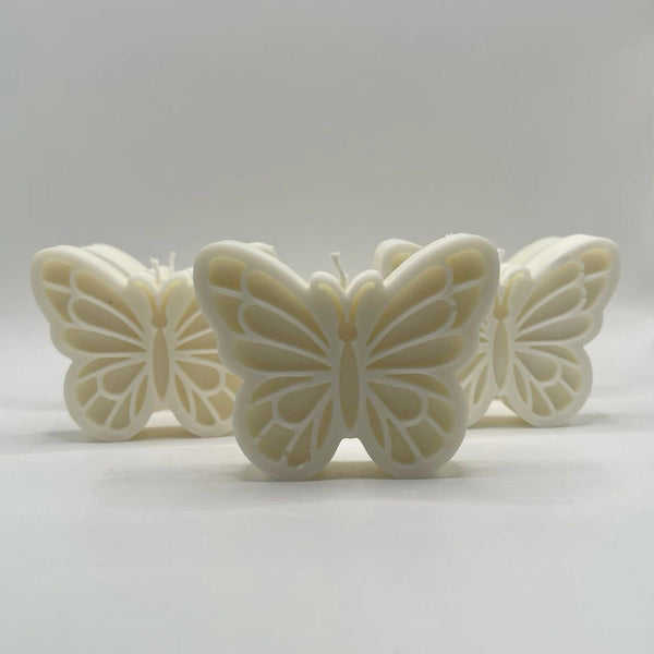 Cream-colored butterfly-shaped candles with detailed wing patterns arranged on a light surface.