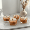 Set of four orange blossom scented candles in clear glass jars with white floral wax tops on a marble tray.