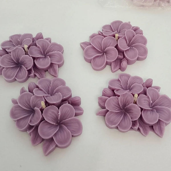 Set of four lavender flower-shaped candles with detailed petals and small central wicks.
