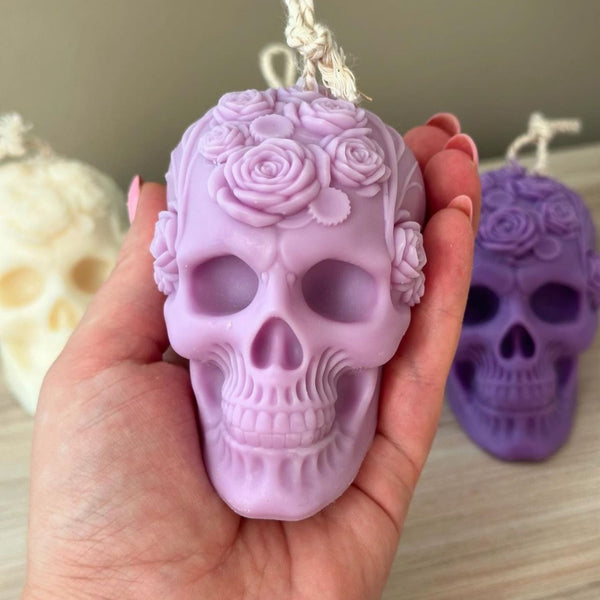 Lavender skull candle with intricate rose and leaf carvings held in hand.