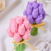 Pink and purple tulip-shaped candles bundled with yellow ribbon on green stems.