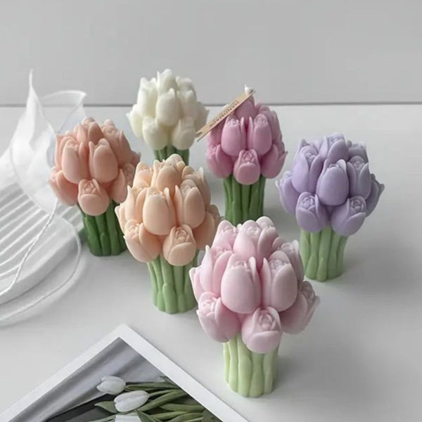 Set of six tulip-shaped candles in pastel shades of peach, white, purple, and pink with green stems displayed on a white.