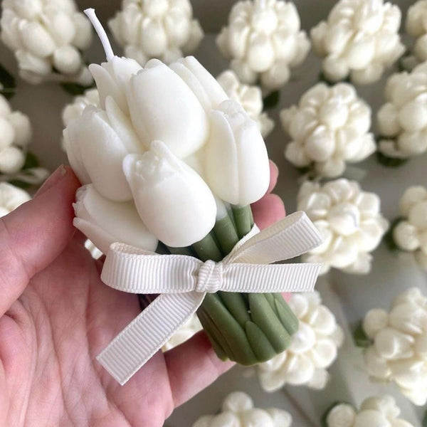 White tulip-shaped candle bouquet with green stems and a beige ribbon bow.