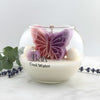 Round glass jar candle with a two-tone purple and pink butterfly-shaped wax centerpiece and white wax base labeled Cool Water.