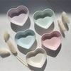 Set of five pastel-colored heart-shaped multipurpose trays in pink, blue, green, beige, and lavender on a white surface.