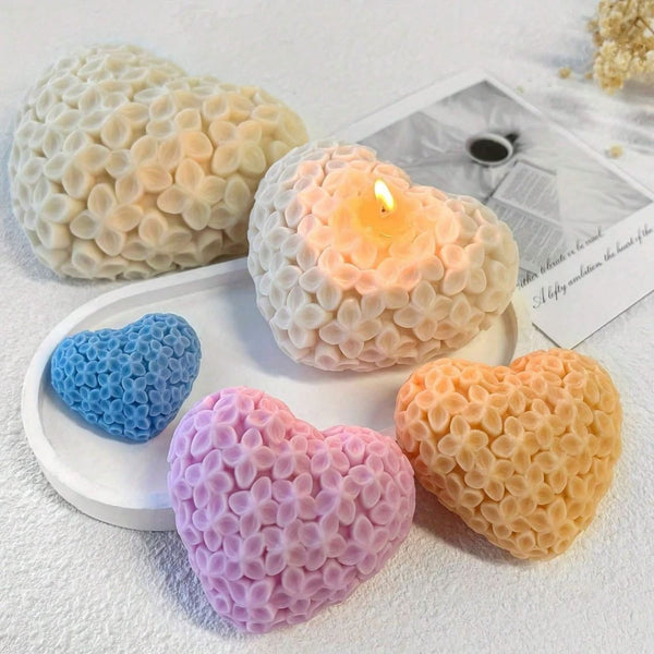 Heart-shaped candles with intricate floral patterns in white, blue, pink, and peach colors on a white surface.