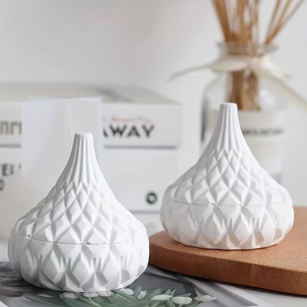 White ceramic jar with textured diamond and stripe patterns, rounded shape, narrow top opening, displayed on wooden surface.