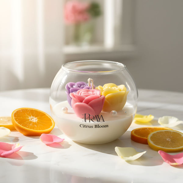 Round glass jar candle with pink, purple, and yellow rose-shaped wax flowers on white base labeled Citrus Bloom.