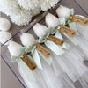 Set of five white tulip-shaped candles with green ribbons and custom brown tags, displayed in clear packaging.