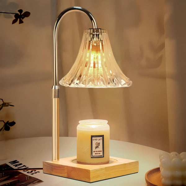 Silver metal candle warmer lamp with clear fluted glass shade and wooden base, warming a lit white jar candle.