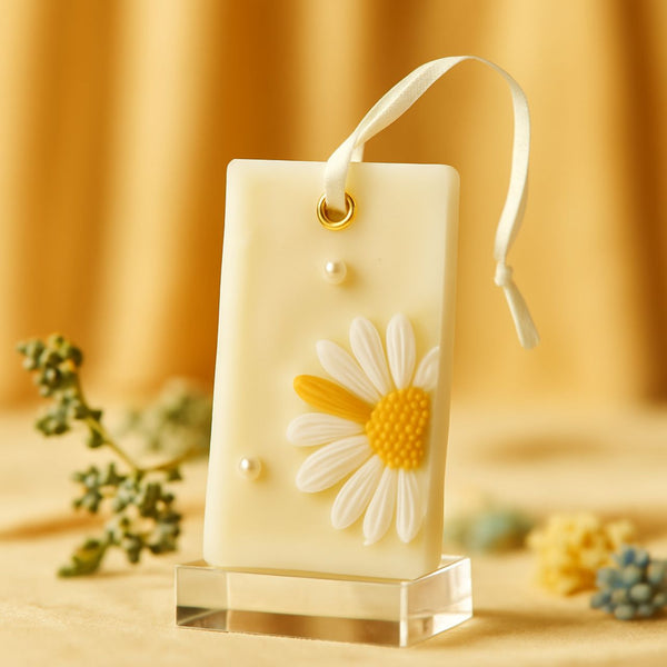 Creamy white soy wax sachet with a textured yellow and white daisy and pearl accents, hanging ribbon.