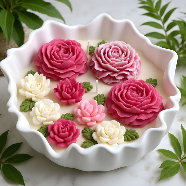 White scalloped ceramic bowl with creamy wax and pink, red, and white rose-shaped floral candles.