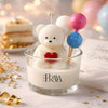 White teddy bear candle with red heart in clear glass jar, decorated with pink and blue balloon sticks.
