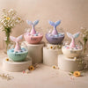 Round pastel-colored jar candles with fish-tail lids in green, pink, purple, and cream shades.