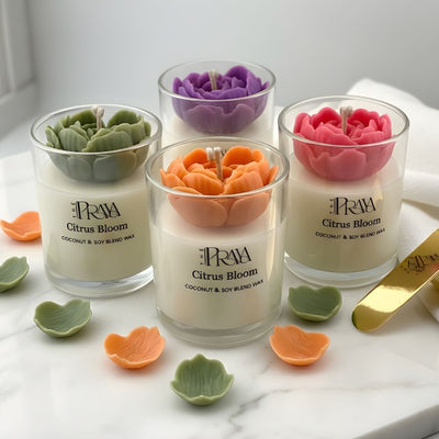 Set of three glass jars with orange, pink, and purple 3D heart-shaped flower candles on white marble surface.