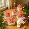 Lotus flower jar candles in pink and purple with creamy wax, lit and decorated with a small angel figurine tag.