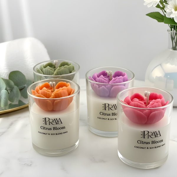 Set of three glass jar candles with 3D flower designs in orange, purple, and pink on white wax.