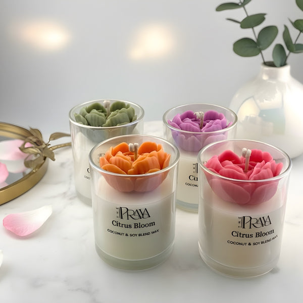 Set of four glass jar candles with 3D heart-shaped flowers in orange, pink, purple, and green on white surface.