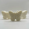 Cream-colored butterfly-shaped candles with detailed wing patterns arranged on a light surface.