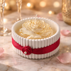 White ceramic jar with ribbed design, decorated with red ribbon and small rose embellishment, filled with swirled.