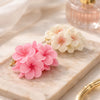 Pink and white cluster floral aromatic flower candles on a marble tray with gold accents.