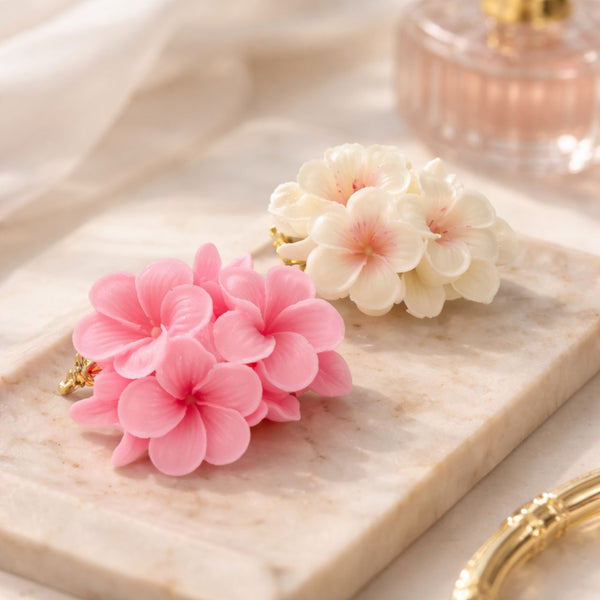 Pink and white cluster floral aromatic flower candles on a marble tray with gold accents.