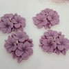 Set of four lavender flower-shaped candles with detailed petals and small central wicks.