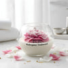 Round glass jar candle with white wax and a pink peony flower wick labeled Mahogany Teakwood.