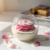 Round glass jar candle with a detailed pink peony flower wax design and mahogany teakwood scent label.