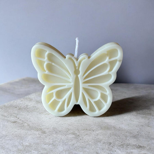 Creamy white butterfly-shaped candle with detailed wing patterns and a central wick.