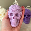 Lavender skull candle with intricate rose and leaf carvings held in hand.
