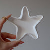 Handmade white ceramic star-shaped tray with textured edges held by a hand.