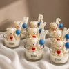 Candle holders with teddy bears, hearts, and letters on a white surface