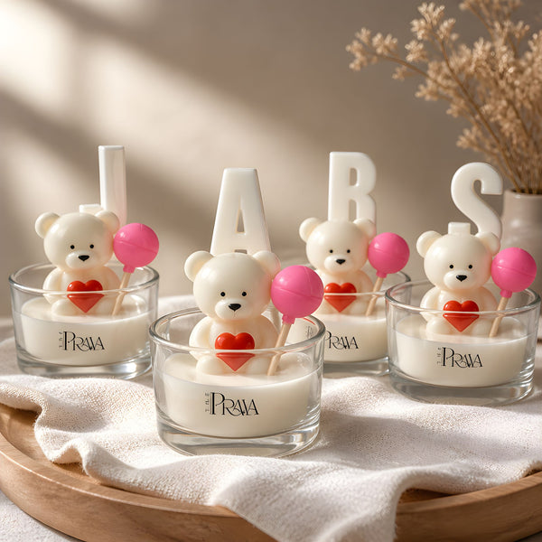 Candle holders with teddy bear designs and 'PRAYA' branding on a wooden tray.
