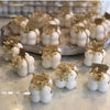 Set of white bubble candles with dried flower accents and rustic tags arranged on a tray and marble surface.