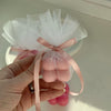Hand holding a pale pink bubble candle tied with sheer white fabric and a pink satin ribbon.