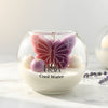 Round glass jar candle with a pink and purple butterfly-shaped wax center and white wax base labeled "Cool Water".