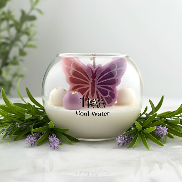 Round glass jar candle with purple and pink butterfly design and white wax labeled Cool Water.