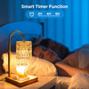 Electric candle warmer lamp with gold metal frame and textured glass shade on wooden base next to sleeping person.