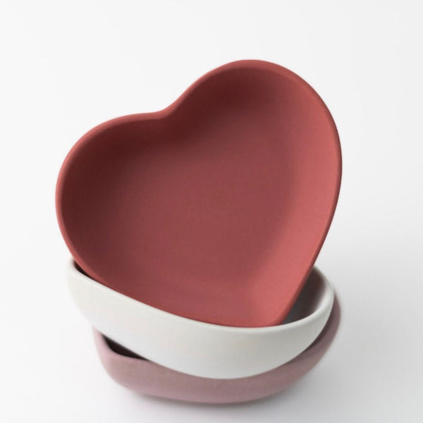 Stack of heart-shaped multipurpose trays in pink, white, and mauve colors with smooth matte finish.