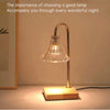 Electronic candle warmer lamp with curved brass arm and ribbed glass shade on wooden base.