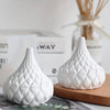 White ceramic jar with textured diamond and stripe patterns, rounded shape, narrow top opening, displayed on wooden surface.