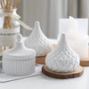 Set of three white ceramic jars with textured striped and quilted patterns, wooden base on one jar.