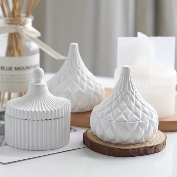 Set of three white ceramic jars with textured striped and quilted patterns, wooden base on one jar.